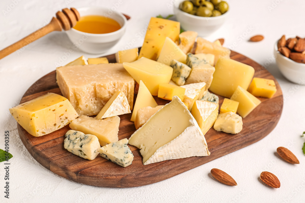 Wooden board with pieces of tasty cheese on light background