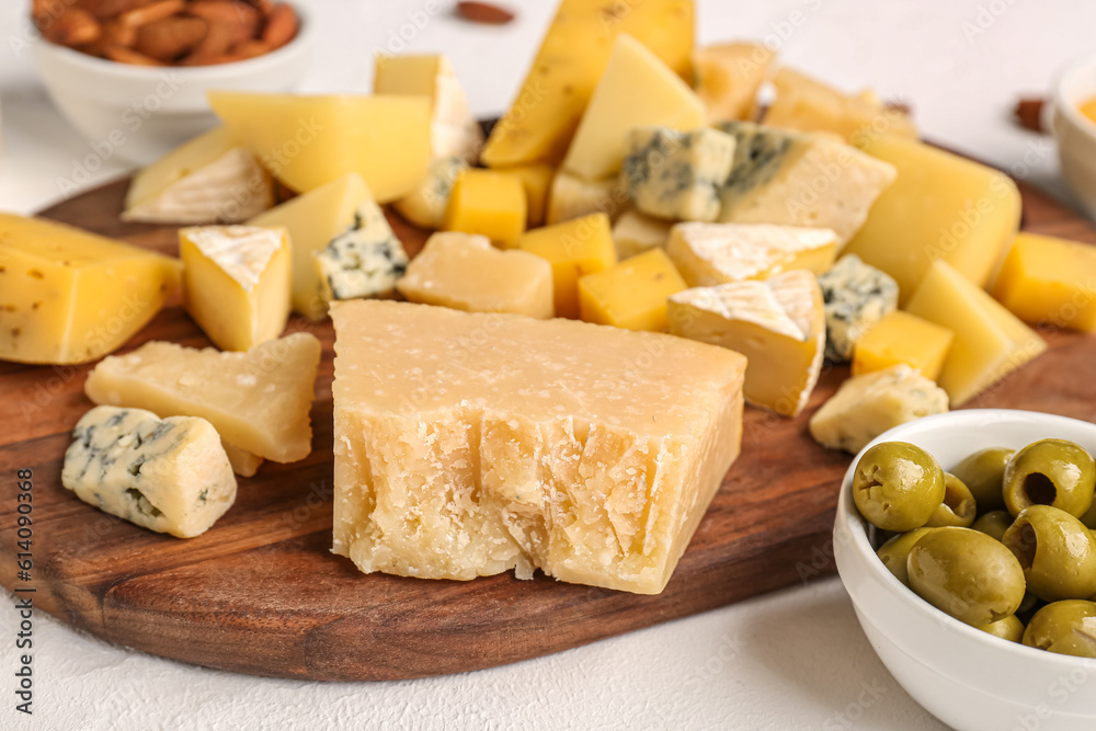 Wooden board with pieces of tasty cheese on light background