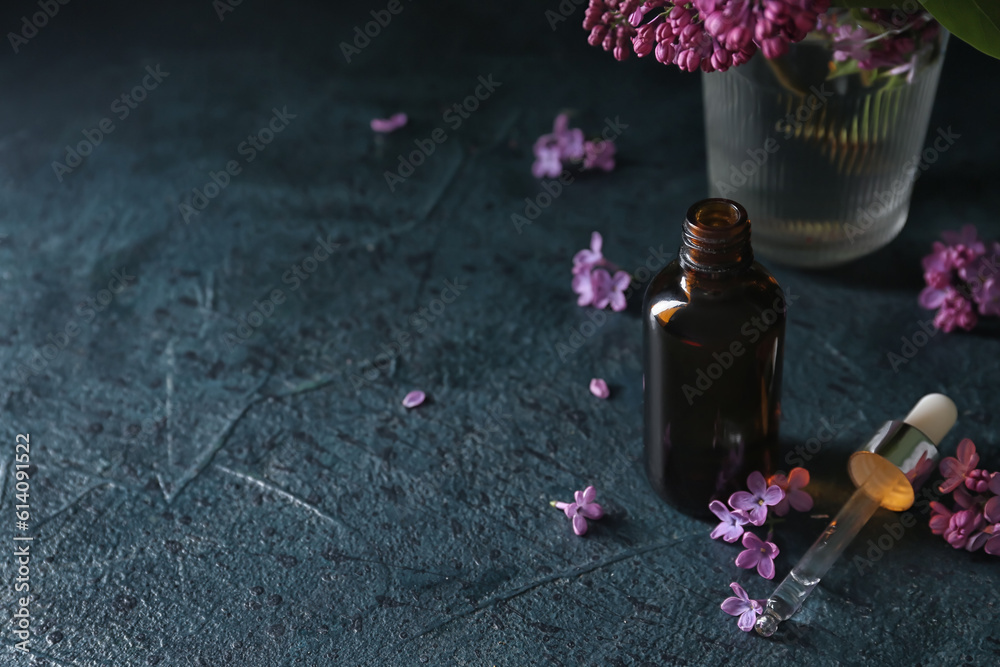 Bottle of cosmetic oil with beautiful lilac flowers on dark table