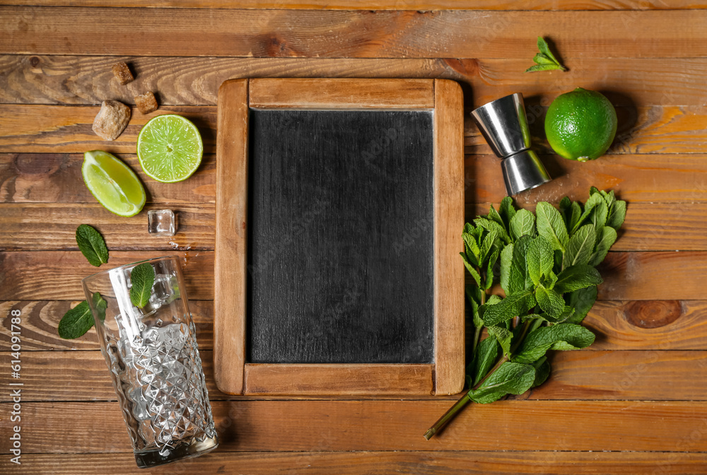 Glass with ice, measure cup and ingredients for preparing mojito on wooden background