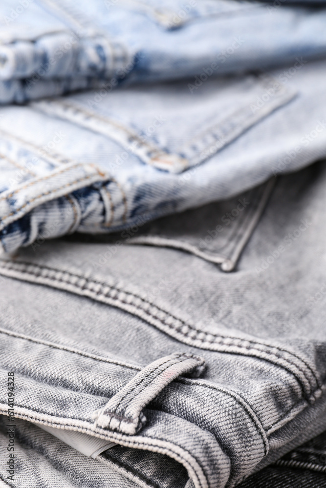 Different stylish folded jeans as background, closeup