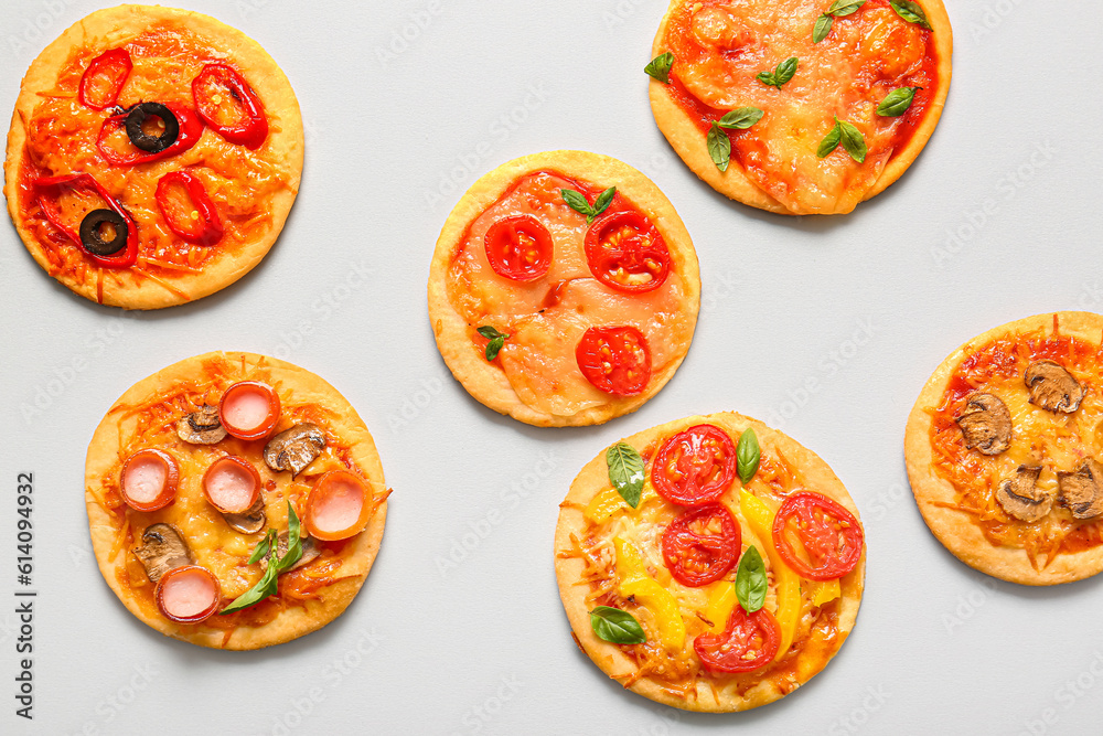 Different tasty mini pizzas on grey background