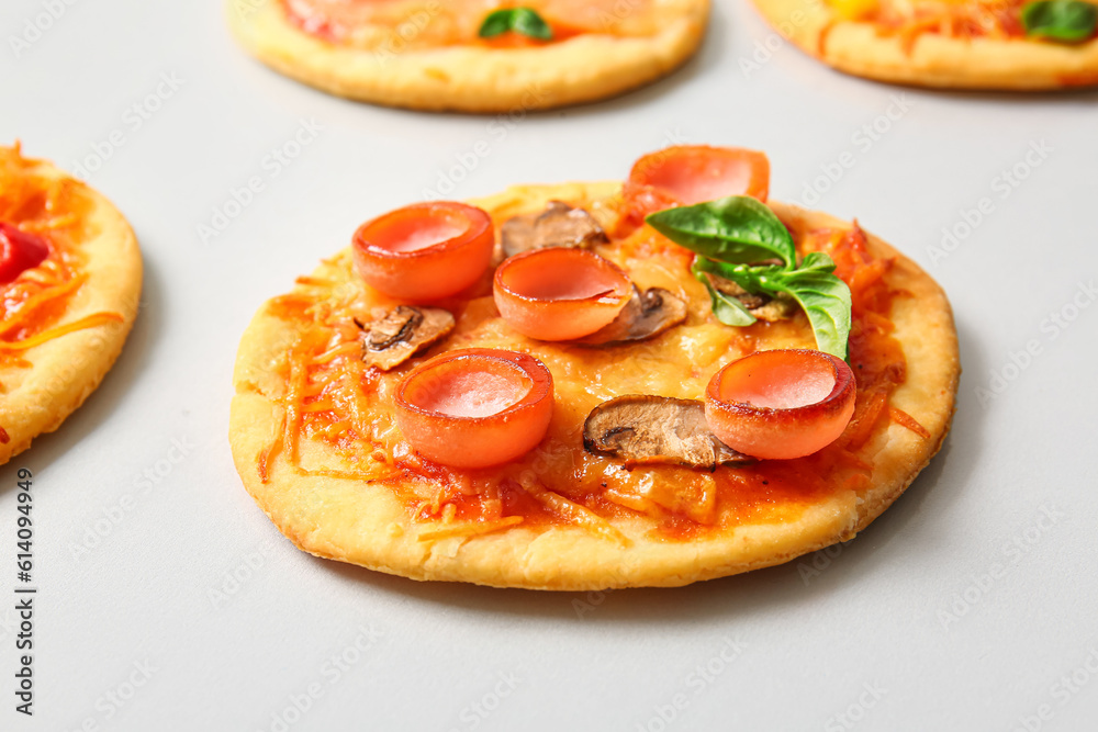 Different tasty mini pizzas on grey background