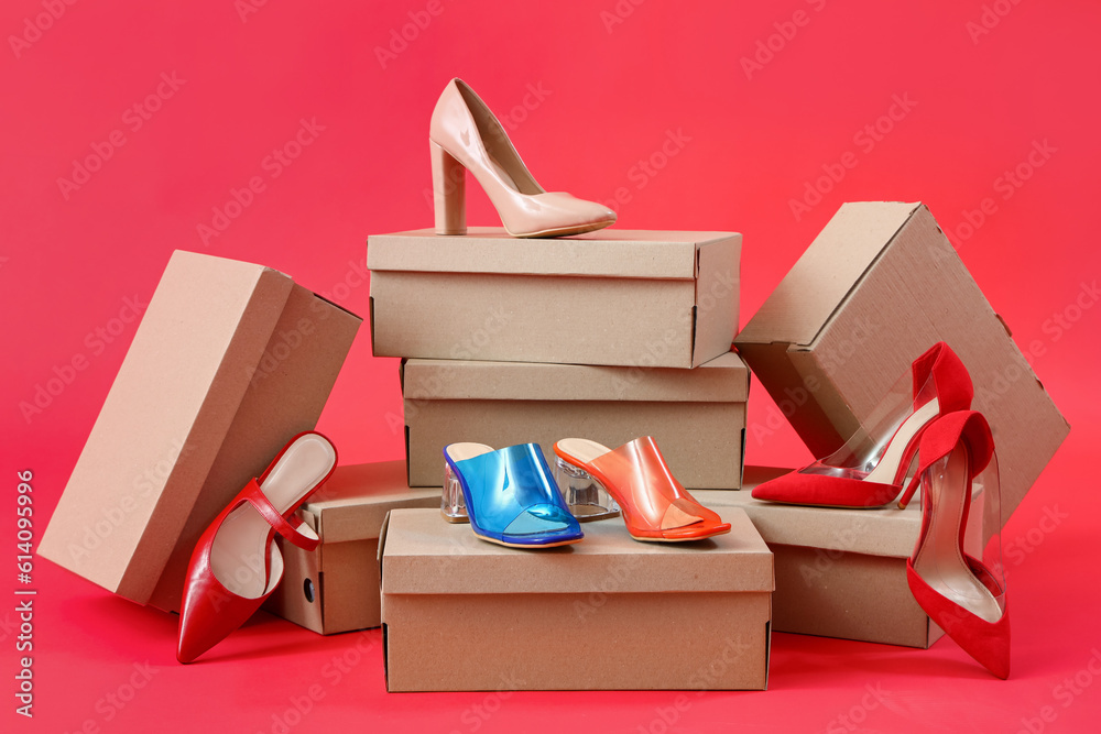 Cardboard boxes with different stylish high-heeled shoes on red background