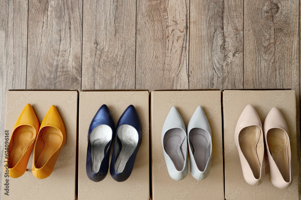 Cardboard boxes with stylish high-heeled shoes on light wooden background