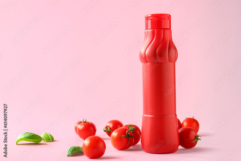 Bottle of ketchup and tomatoes on pink background