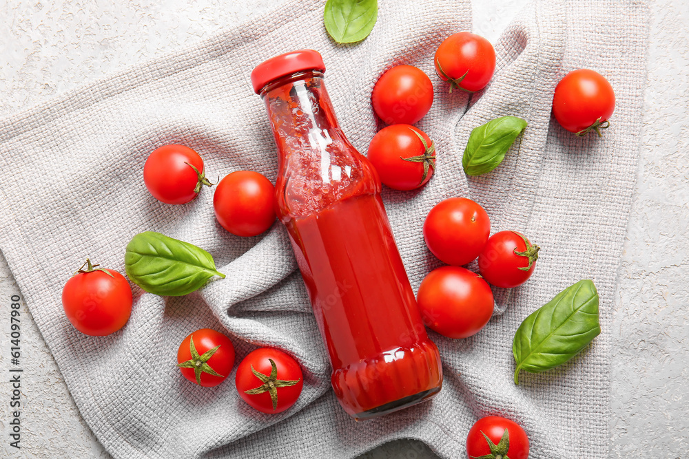 Glass bottle of ketchup and tomatoes on white background