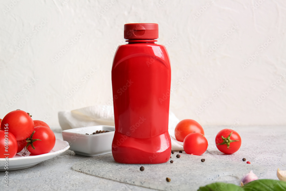 Board with bottle of ketchup and tomatoes on white background