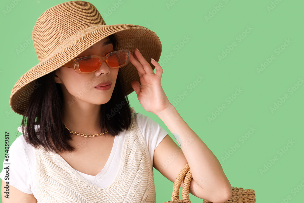 Beautiful Asian woman in stylish sunglasses on green background, closeup