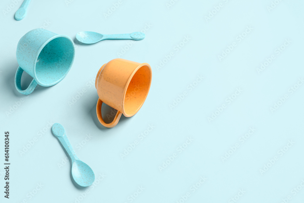 Different colorful cups with spoons on blue background. Childrens Day celebration