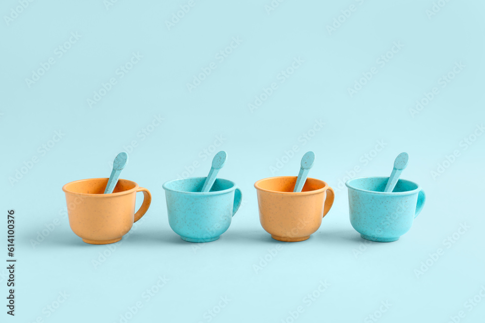 Different colorful cups with spoons on blue background. Childrens Day celebration