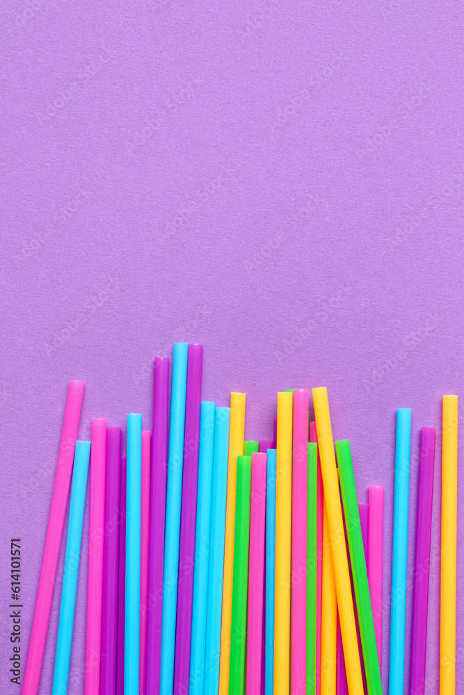 Different plastic straws on purple background