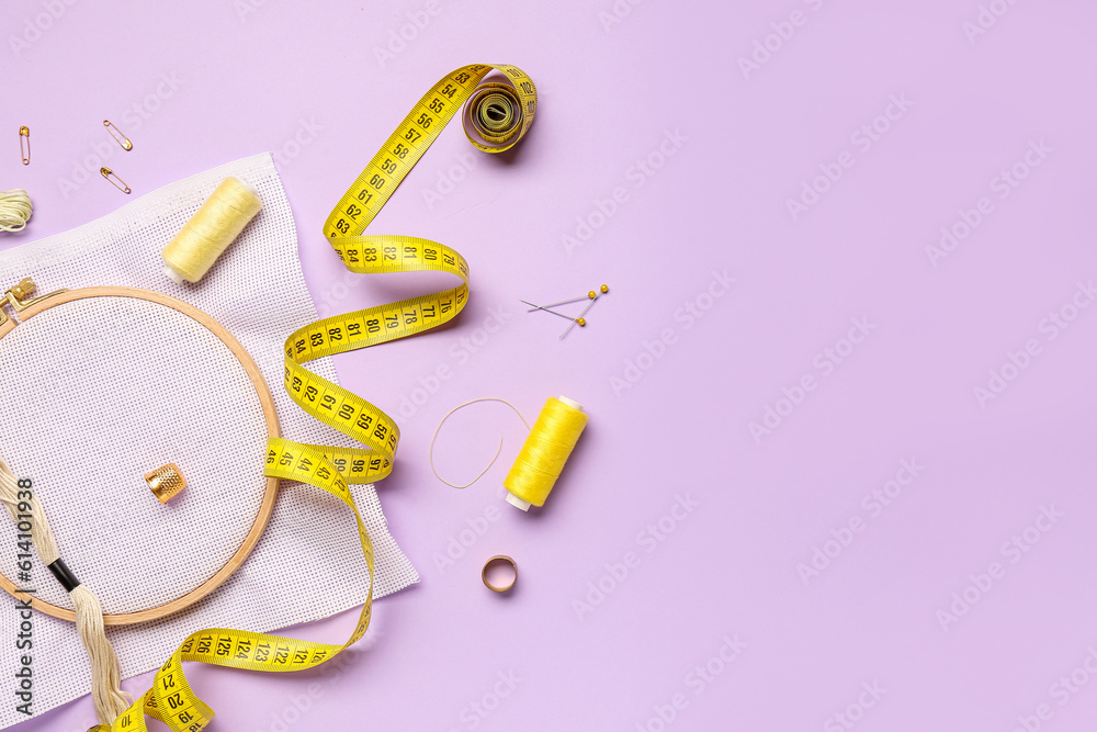 Embroidery hoop with canvas, mouline threads and measuring tape on lilac background