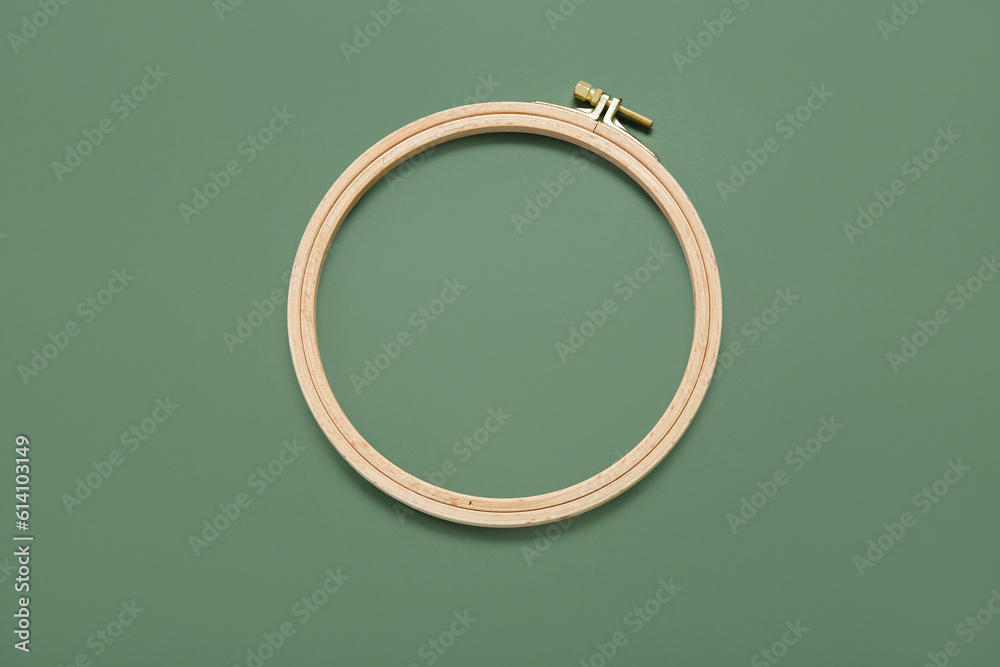 Wooden embroidery hoop on dark green background