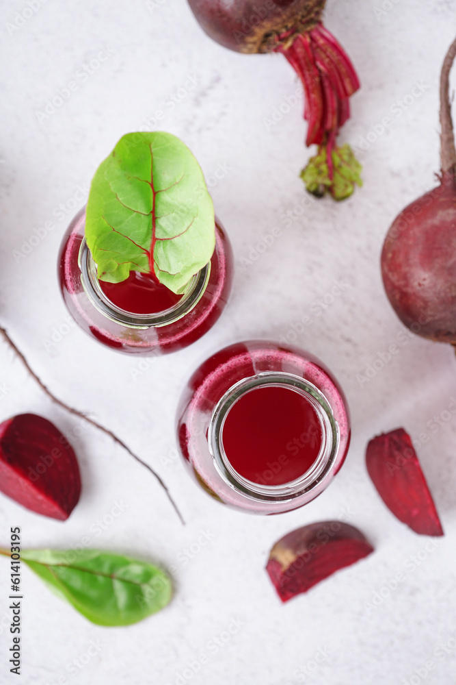 Bottles of fresh beetroot juice on light background