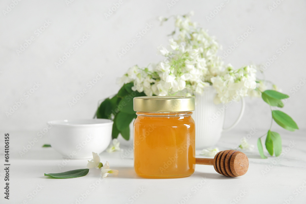 Bowl and jar of honey with flowers of acacia on light background, closeup