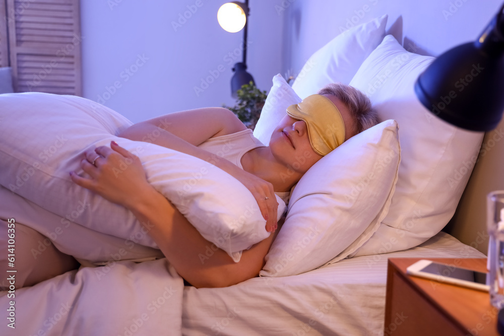 Young woman with mask sleeping in bed at night