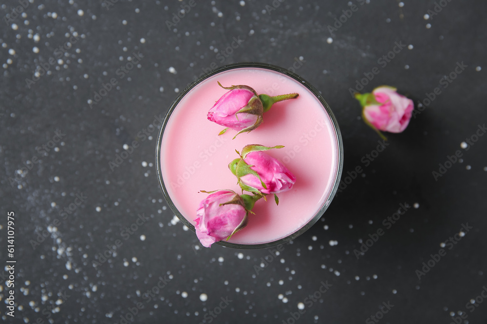 Glass of panna cotta with beautiful pink rose flowers on black table