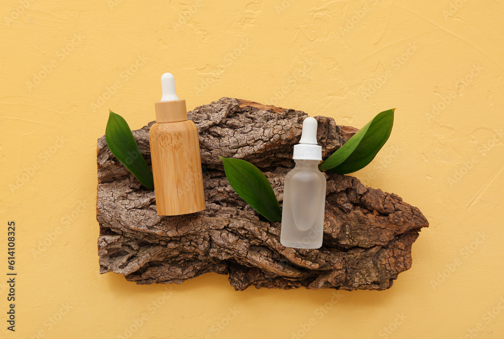 Composition with bottles of essential oil, tree bark and plant leaves on color background