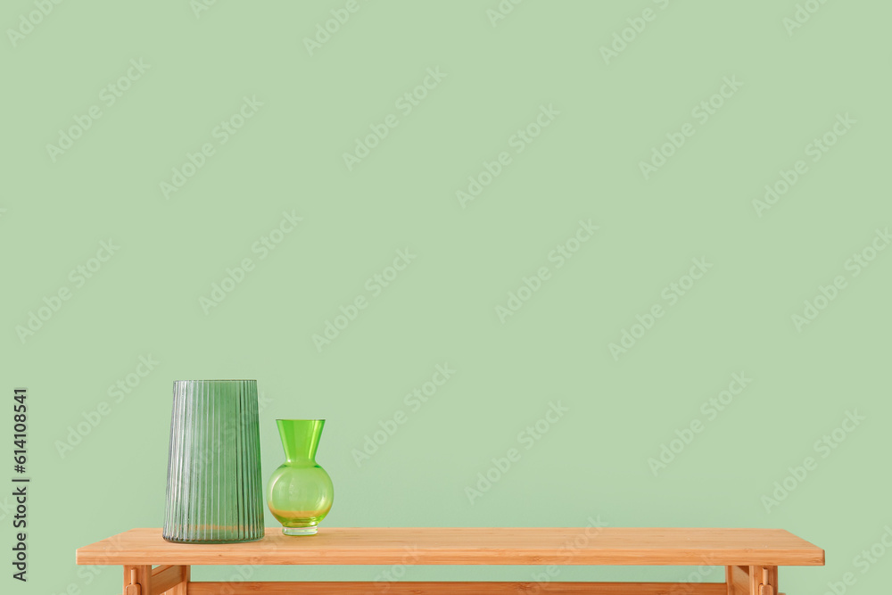 Wooden table with empty vases near green wall