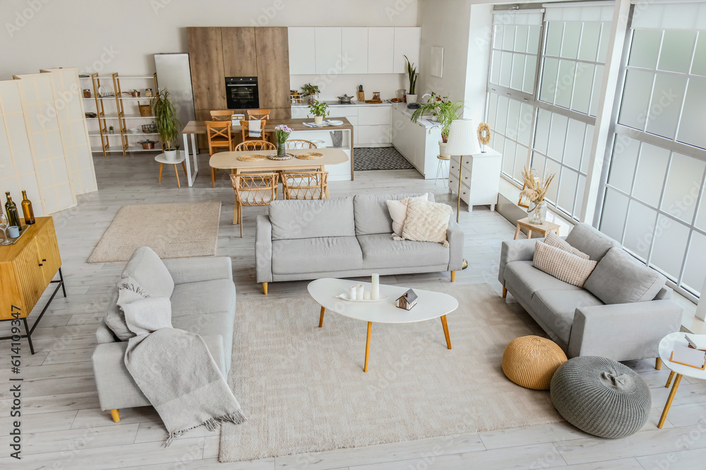 Interior of light open plan kitchen with grey sofas and coffee table