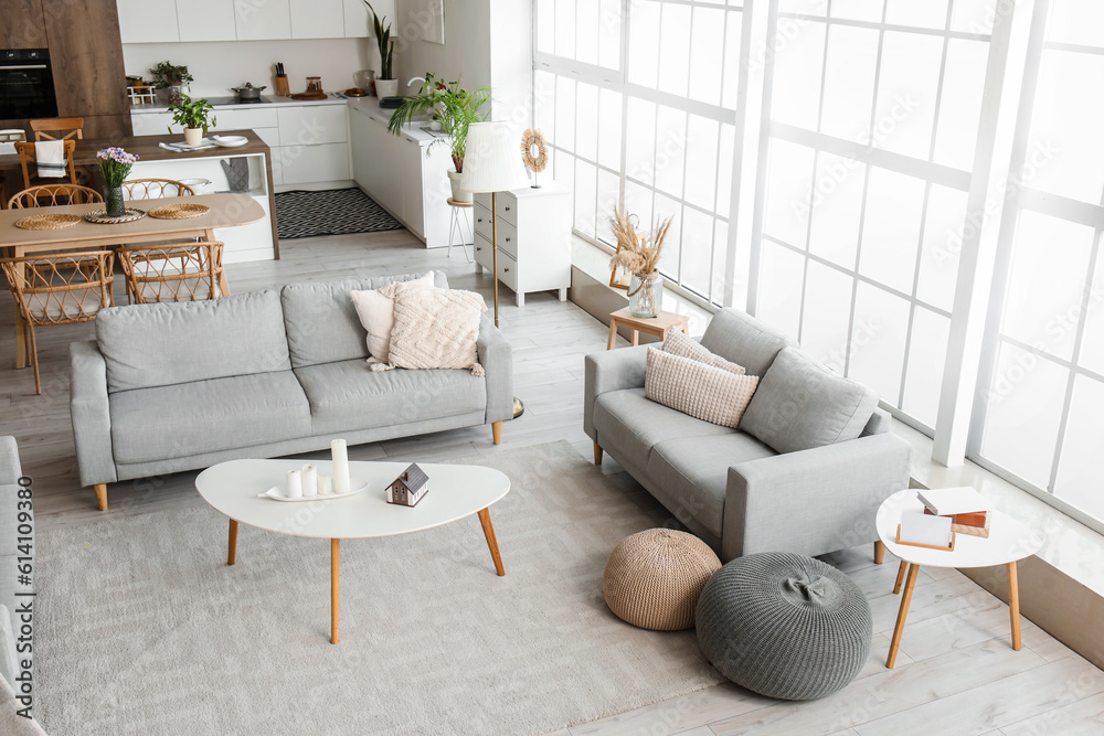 Interior of light open plan kitchen with grey sofas and coffee table