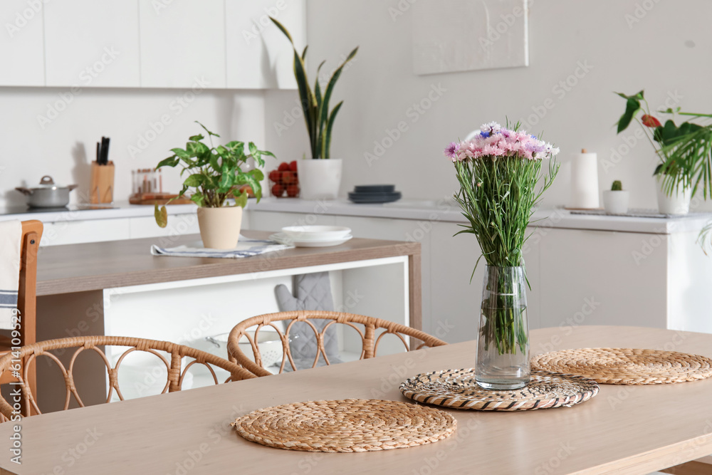 Vase with beautiful cornflowers on dining table in kitchen