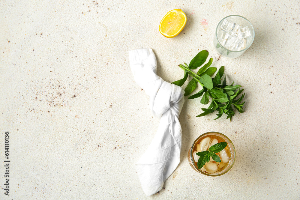 Glass of ice tea with mint and lemon on white background