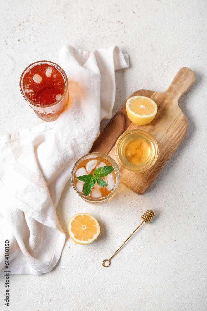 Glasses of ice tea and board with lemon on white background