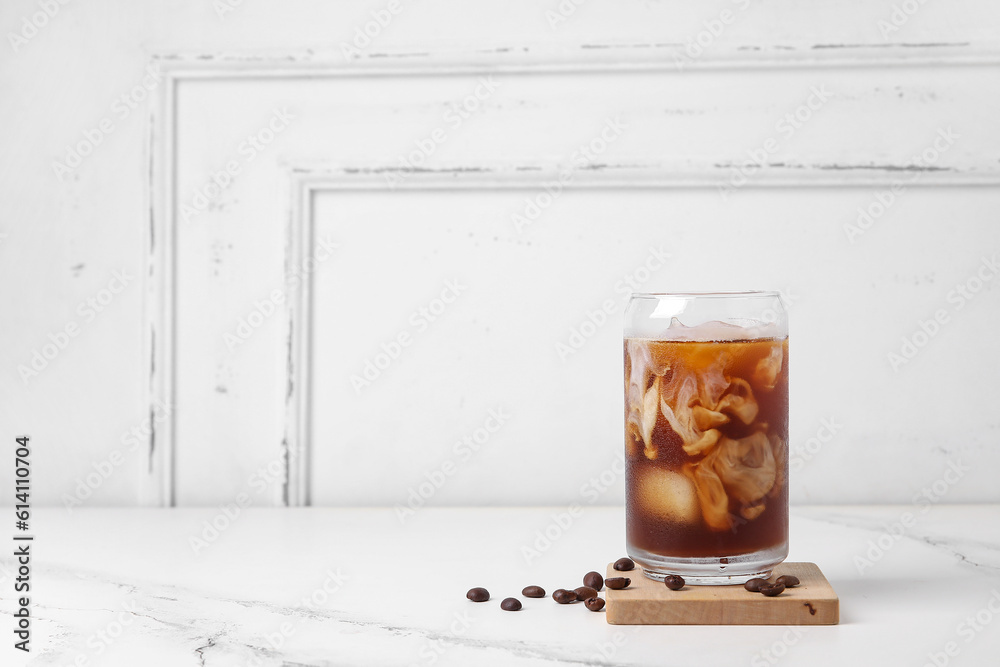 Glass of tasty ice coffee with milk on table