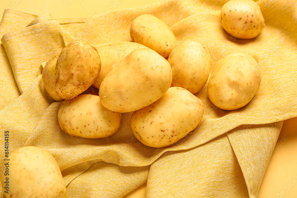 Raw baby potatoes on yellow background