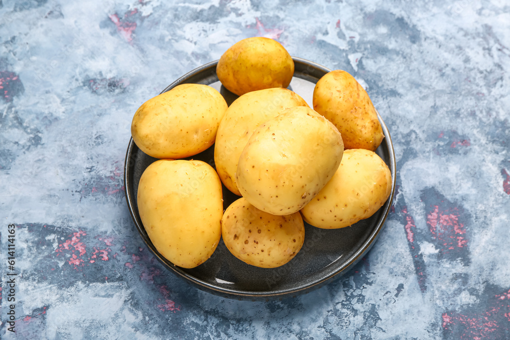 Tray with raw baby potatoes on blue background