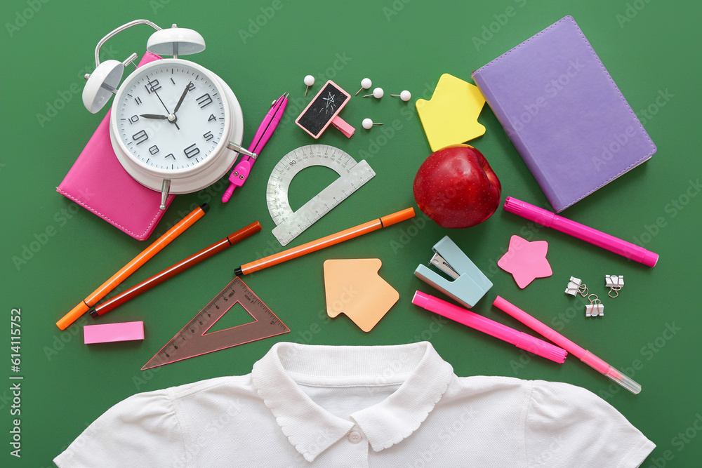 Stylish shirt with apple, alarm clock and different stationery on green background