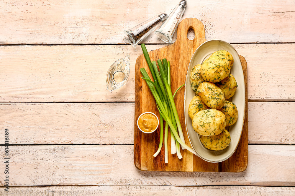 Plate of boiled baby potatoes with dill and green onion on white wooden background