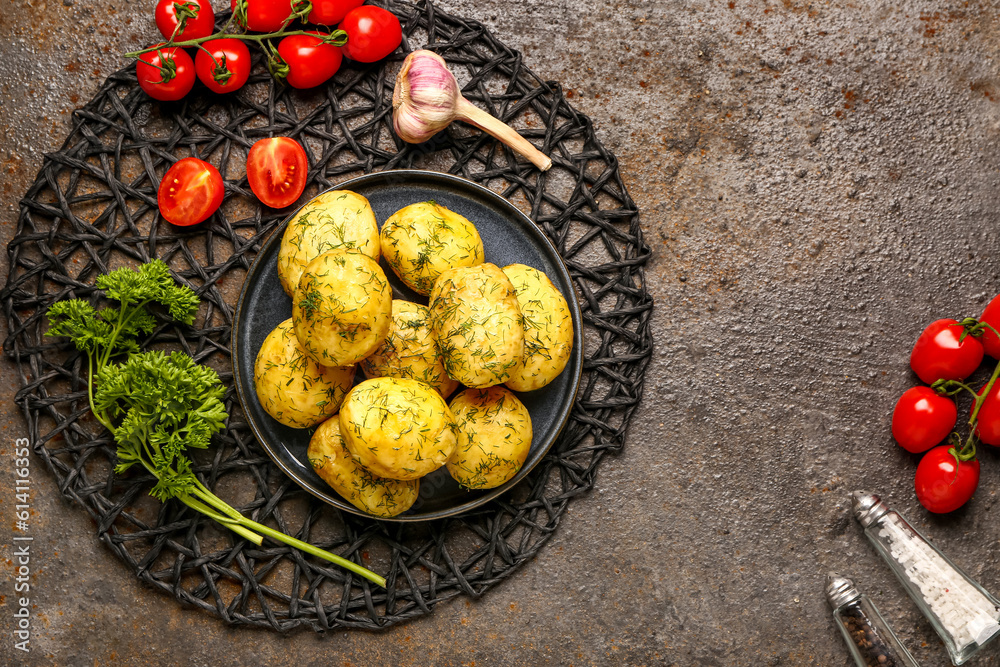 Plate of boiled baby potatoes with dill and tomatoes on dark background