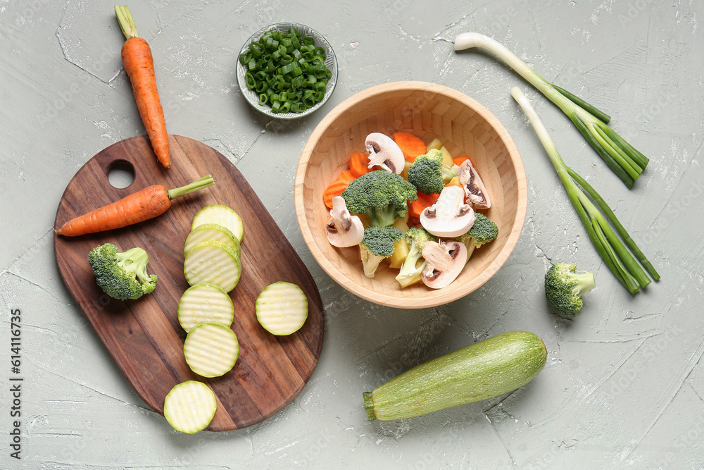 Bowl with fresh vegetables on grey background