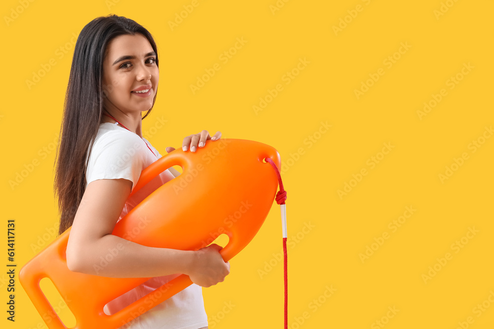 Female lifeguard with board on yellow background