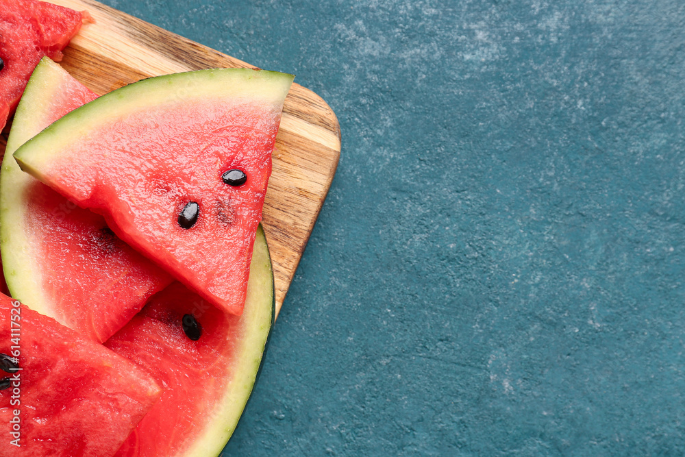 Board with pieces of fresh watermelon on blue background