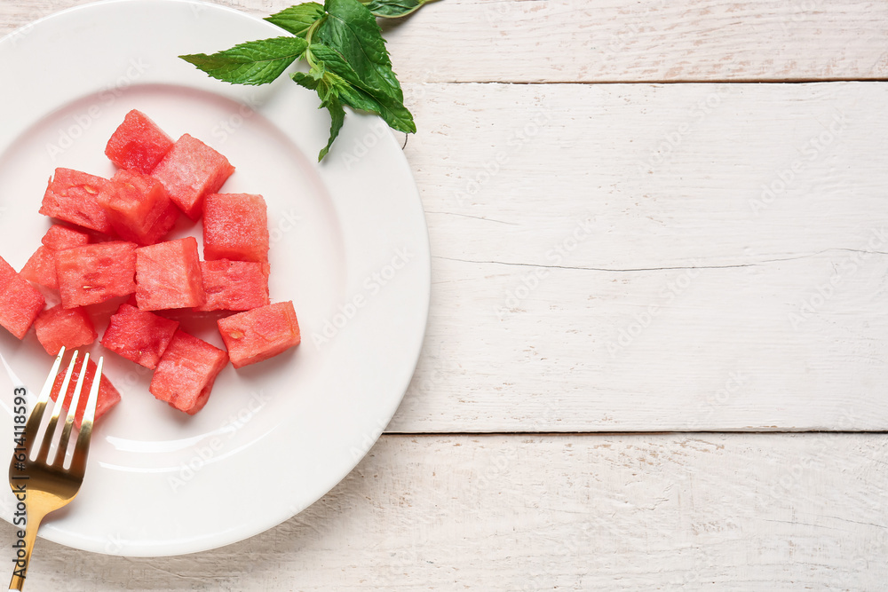 Plate with pieces of fresh watermelon and mint on white wooden background