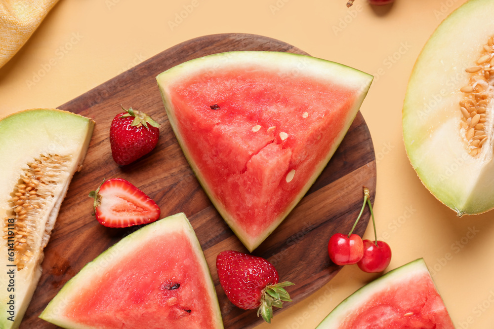 Board with pieces of fresh watermelon and different berries on yellow background