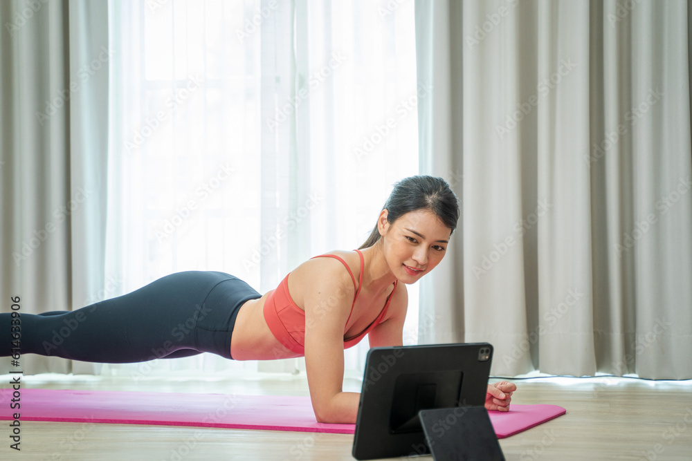 Young woman using tablet pc doing yoga stretching yoga online at home,Entertainment and education on