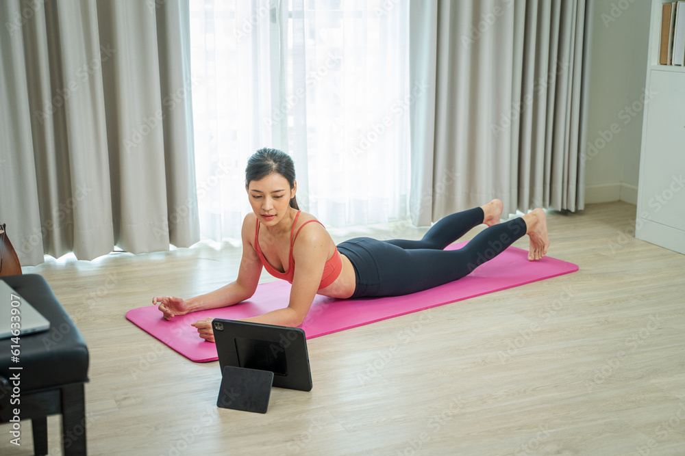 Young woman using tablet pc doing yoga stretching yoga online at home,Entertainment and education on