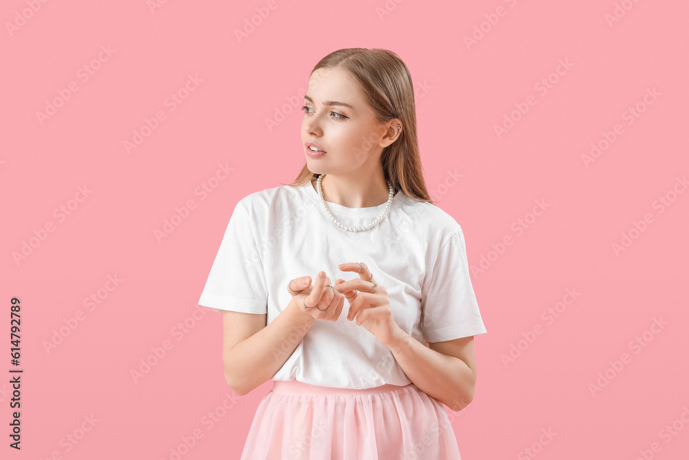 Young woman in t-shirt counting on pink background