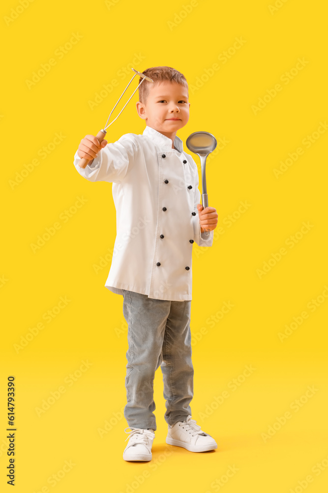 Cute little chef with supplies on yellow background