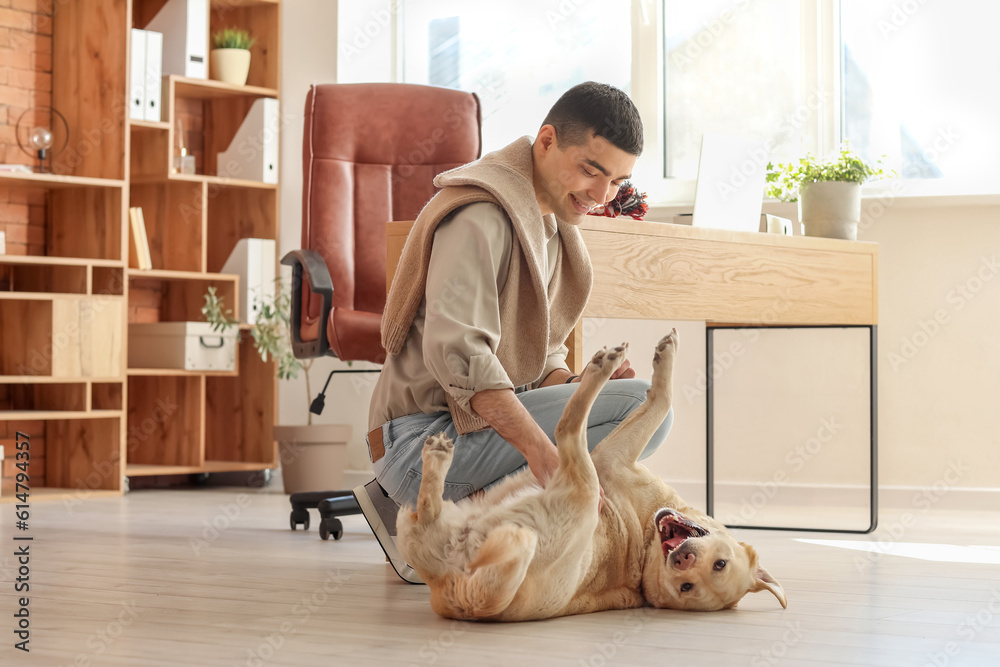 Young man with cute Labrador dog in office