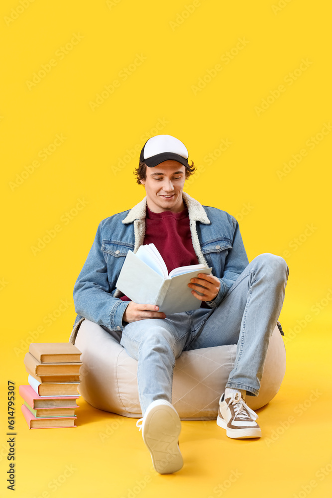 Young man reading book on yellow background