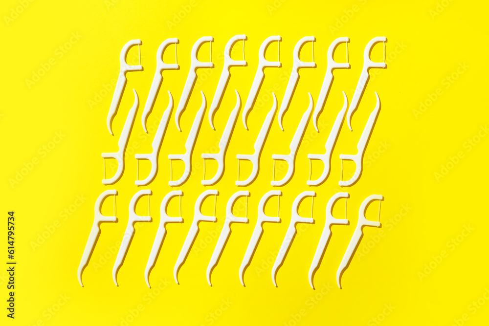 Many floss toothpicks on yellow background