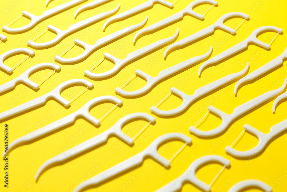 Many floss toothpicks on yellow background