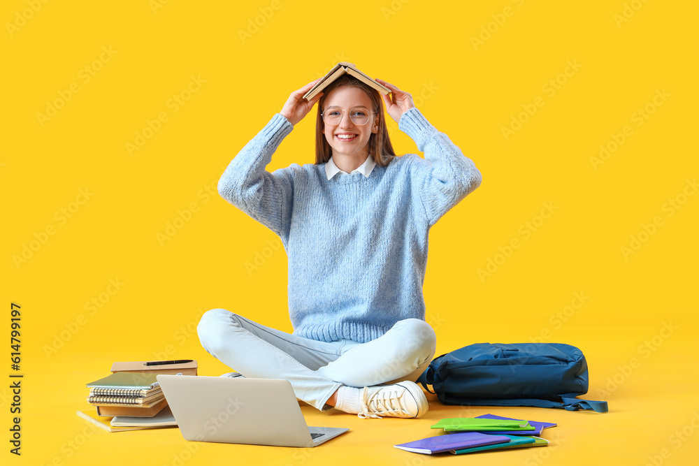 Female student with book studying on yellow background