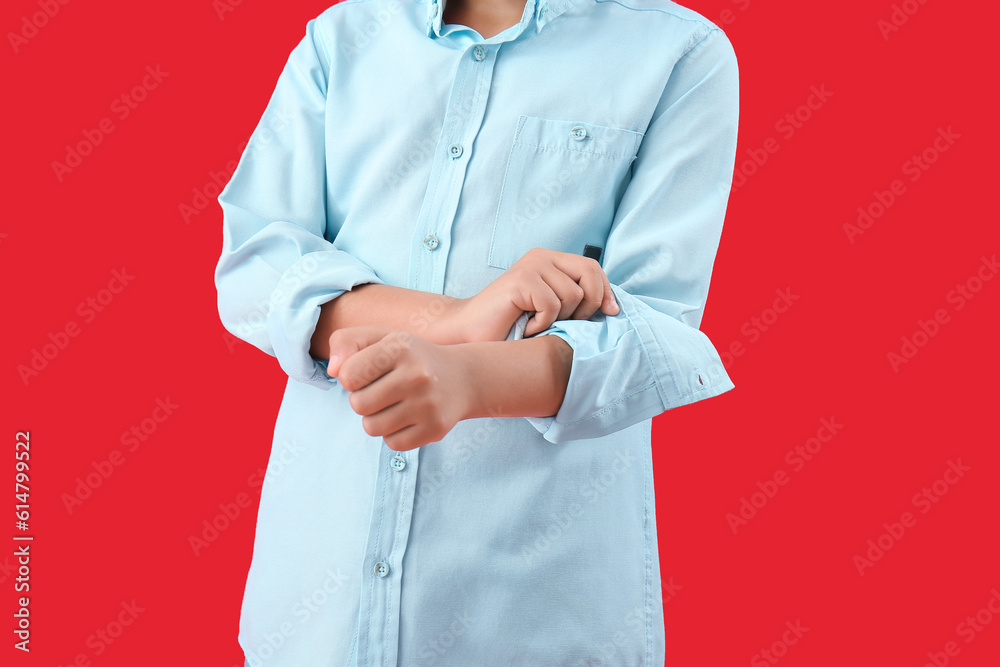 Little boy rolling up his sleeve on red background